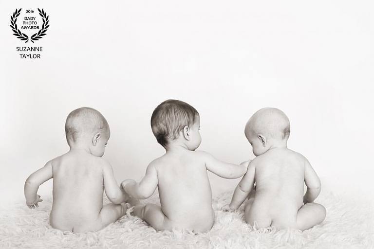 Award Winning image by Red Deer Photographer, Suzanne Taylor of triplets sitting together.