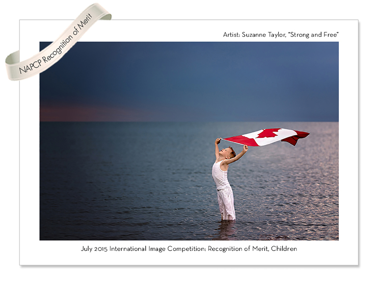 Young boy dressed in white holding the Canada Day Flag above his head with the wind blowing it