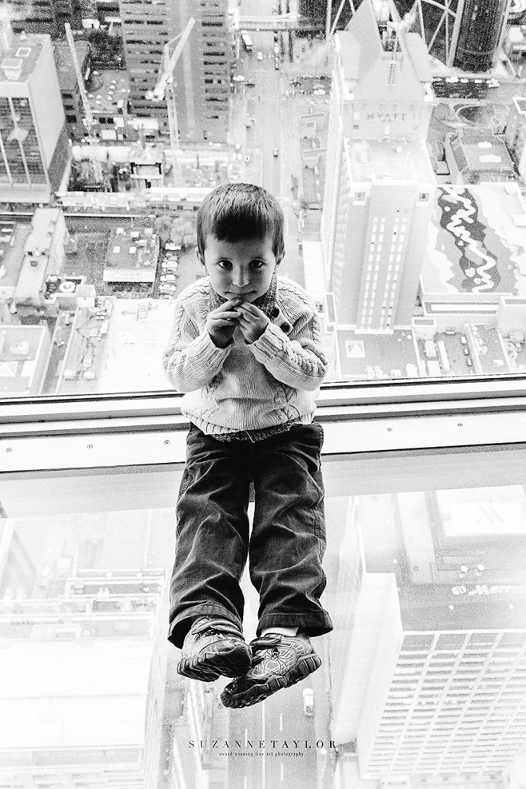 Small boy sits on glass floor of Calgary Tower