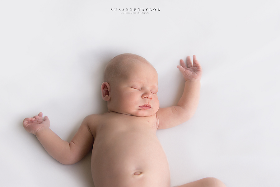 A newborn boy lays on his back resting during his newborn session