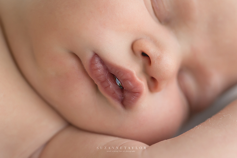 A newborn boy blows a small bubble on his lips while sleeping