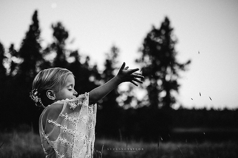 A child throwing seeds to the wind wearing a wardrobe piece from the Suzanne Taylor Photography Dress Bank.