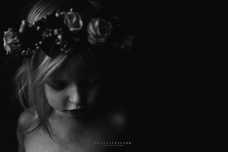 A young girl looks down while wearing a floral crown processed in Black and White by Suzanne Taylor Photography. - Red Deer Children Photographer.
