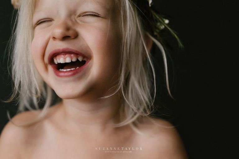A young girl smiles with her eyes shut taken by Suzanne Taylor Photography, Red Deer Photographer
