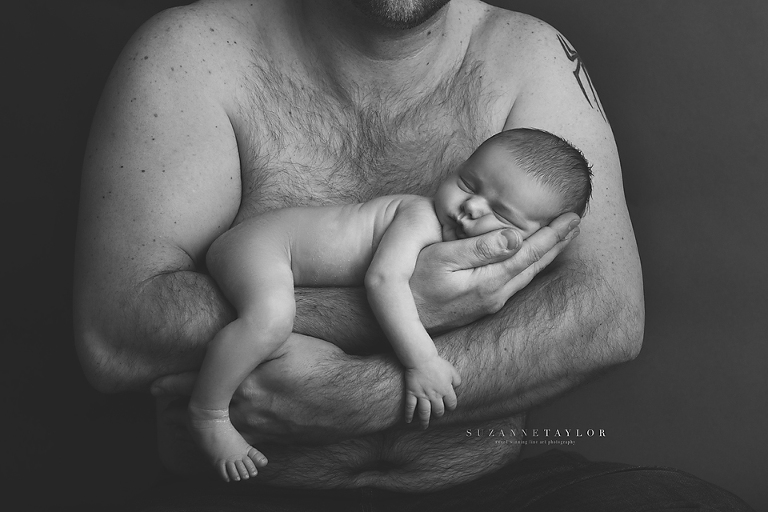 Calgary Newborn is held in his fathers arms by Red Deer Newborn Photographer Suzanne Taylor