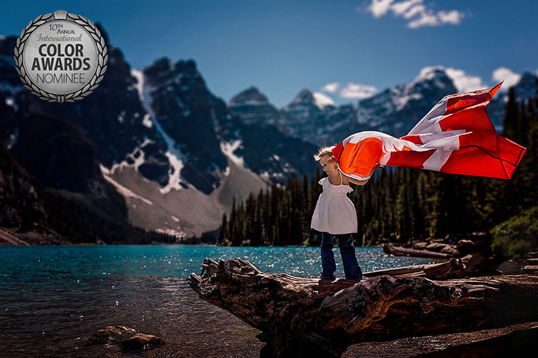 Young girl holds Canada Day flag above her head at Moraine Lake, Alberta in Lake Louise. 