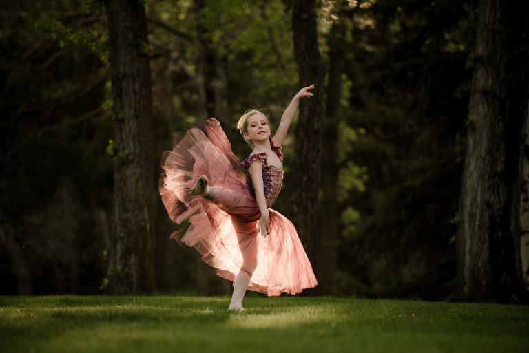 girl in pink outfit dancing in the woods at Gull Lake Alberta photographed by Suzanne Taylor Photography